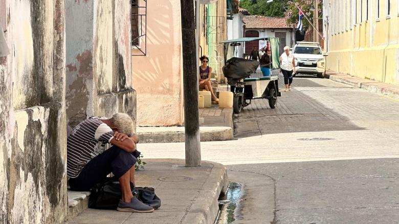 Un anciano sentado en una acera de Camagüey.