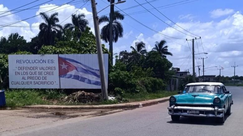 Un carro pasa por delante de una valla de propaganda política en La Habana.