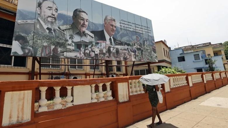 Una mujer camina frente a una valla de propaganda en Cuba.