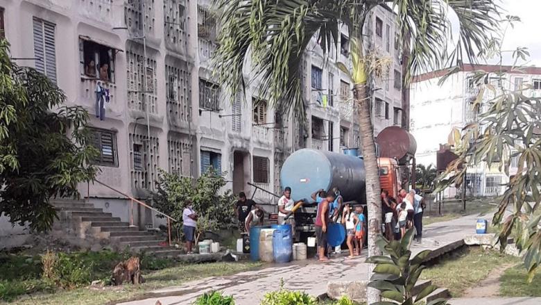 Cubanos cargan agua de una pipa.