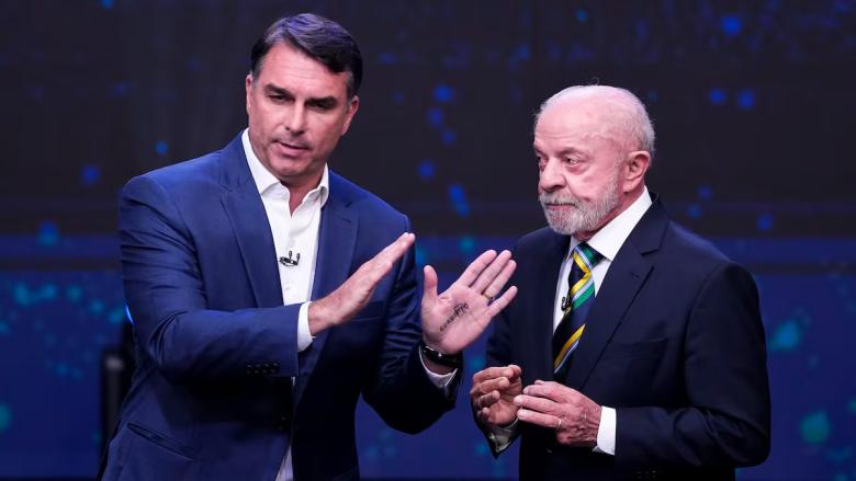 Flávio Bolsonaro, con la palabra "Corrupto" en la palma de su mano, y Lula da Silva, en el debate electoral.