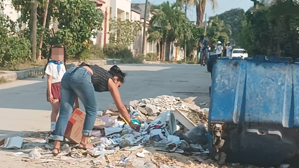 Una madre junto a su hija frente a un basurero en La Habana.