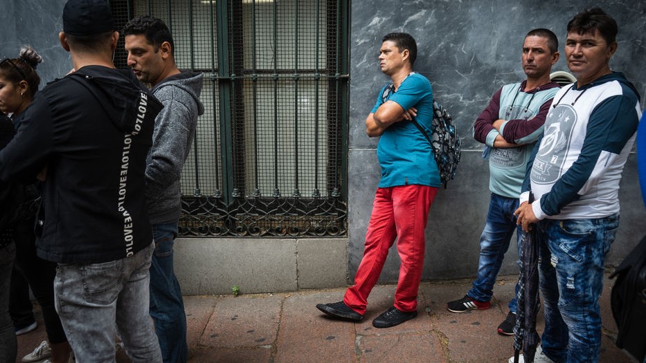 Migrantes hacen cola para regularizar su estatus en una dependencia oficial de Montevideo.